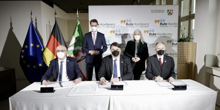 Signing cooperation agreement The three rectors of the UA Ruhr universities sit at a table, with Minister President Hendrik Wüst and Science Minister Isabel Pfeiffer-Poensgen behind them.
