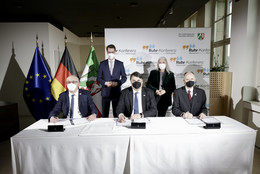 Die drei Rektoren der UA Ruhr-Unis sitzen an einem Tisch, hinter ihnen steht Ministerpräsident Hendrik Wüst und Wissenschaftsministeriin Isabel Pfeiffer-Poensgen