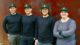 Oktober Maximilian Spiekermann, Jens Ehlhardt, Max Krause und Marén Schwandt (v.l.n.r.) stehen vor einer Rostroten Wand. Alle vier Personen tragen eine rote Cappy mit einem gelben Tropfensymbol und der Unterschrift "Simplyfined".