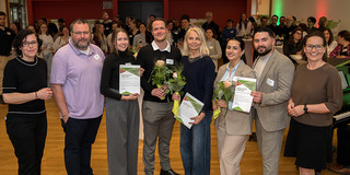 In the photo, eight people are smiling at the camera after the certificates were presented.