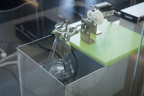 Ein im Glasbehälter befestigter Glaskolben in einem Ultraschallbad.
