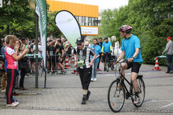 Ein älterer Herr absolviert angestrengt den Campuslauf. Er wird von einem Radfahrer begleitet. Zuschauer applaudieren ihm.