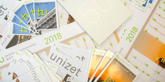 press Various folders of TU Dortmund university are lying on a table.