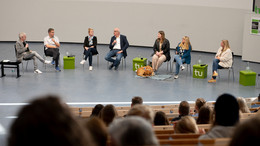 Mehrere Personen sitzen vorne im Audimax in einer Gesprächsrunde zusammen.