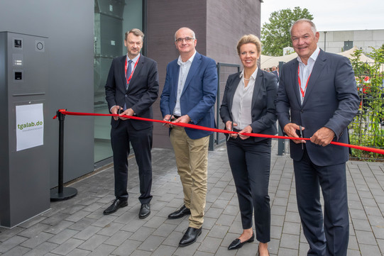 Eröffnung TGA-Labor Vier Personen stehen vor einem roten Band. Alle halten eine Schere in der Hand und schneiden das Band gleichzeitig durch.