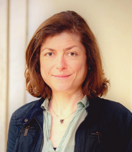 Portrait of a brunette woman in a dark blue corduroy jacket.