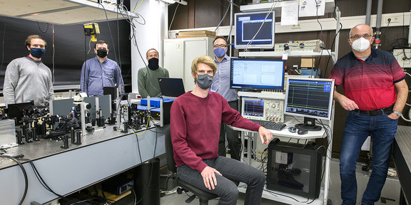 Mehrere Personen mit Maske stehen in einem Labor