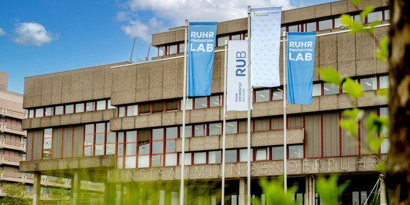 Photo: Flags of Ruhr University Bochum, TU Dortmund, and the Ruhr Innovation Lab fly on the campus of Ruhr University Bochum.