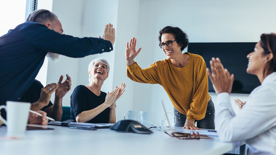 Employees give each other "high five" in meeting room and laugh