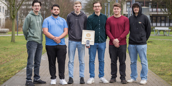 Gruppenbild "Ingenieure ohne Grenzen Challenge" Zu sehen sind fünf Studenten, die in einer Reihe nebeneinander stehen und ihre Erfindung, das "Light Lab Board" in der Hand halten.