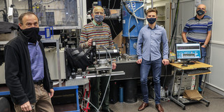 Vier Männer stehen in einem Raum mit experimentellen Maschinen.