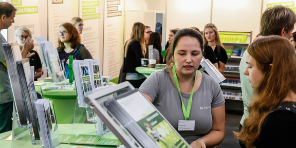 Messe Einstieg An einem Messestand wird eine Schülerin von einer TU-Mitarbeiterin beraten.