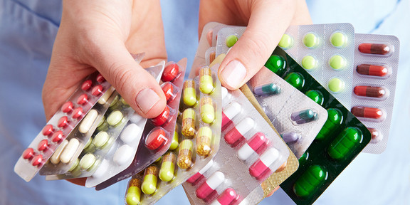 Zwei Hände halten mehrere Tablettenpackungen.