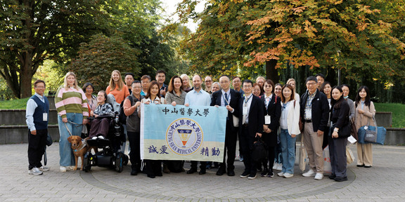 Foto: Es ist eine große Gruppe von Meneschen aus Deutschland und Taiwan zu sehen, die ein Schild hochhalten. Auf dem Schild steht Chung Shan Medical University.