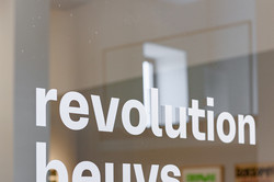 Der Schriftzug "revolution beuys 12.8. bis 17.10." auf einer Glaswand.