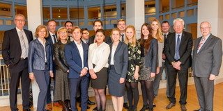 Gruppenfoto mit mehreren Frauen und Männern, die in einem Raum mit Säulen stehen