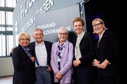 Foto: Eine Gruppe von Personen steht gemeinsam vor einem Eingang mit der Aufschrift „Zugang Hologramme“.