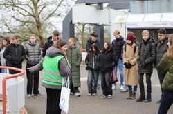 Schüler*innen stehen im Halbkreis um eine Studierende bei einer Campusführung