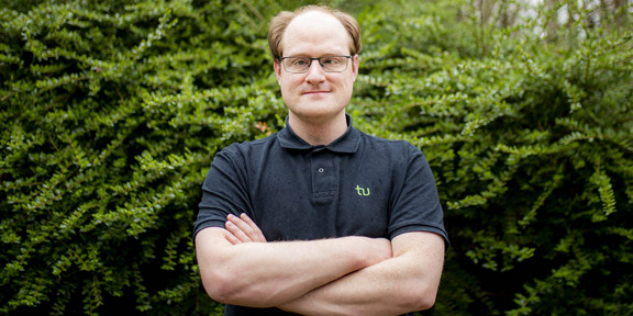 Daniel Horn from the Faculty of Statistics in front of green bushes