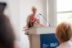 Foto: Prof. Kornelia Freitag von der RUB steht an einem Rednerpult.
