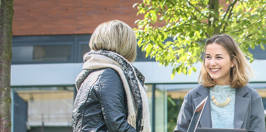 Studierende sitzen vor Gebäude