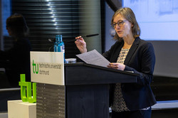 A woman with glasses stands at the lectern and gives a speech.