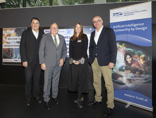 Gruppenfoto: Vor dem Banner des RC Trsut stehen von links nach rechts RUB-Rektor Prof. Martin Paul, Parlamentarischer Staatssekretär Josef Hovenjürgen, RC Trust-Direktorin Prof. Nicole Krämer und TU-Rektor Prof. Manfred Bayer.