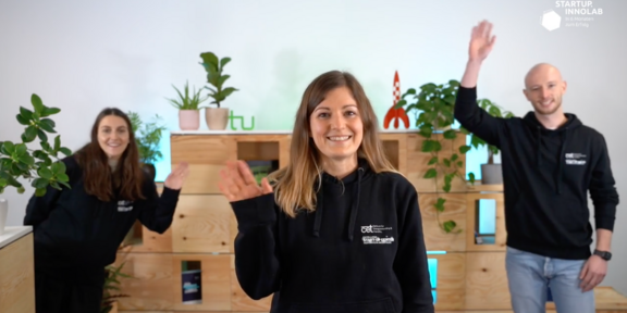 Three people wave at the camera