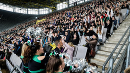 Die neuen Studierenden der TU Dortmund machen eine La-Ola-Welle auf einer gefüllten Tribüne im Fußballstadion.