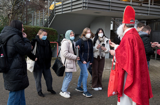 Der Nikolaus verteilt Süßigkeiten an die Studierenden.