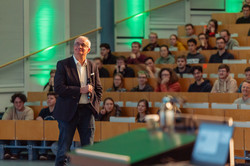 Prof. Manfred Bayer steht vor dem vollbesetzten Hörsaal.