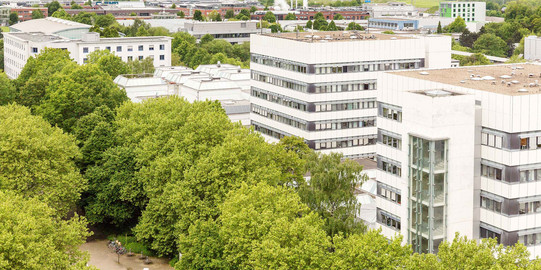 Aerial view o two big white buildings with trees in front of them
