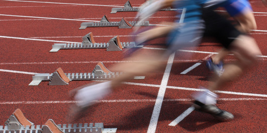 Mehrere Sprinter nebeneinander starten aus Startblöcken.