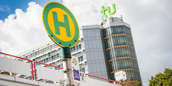 Bus stop sign in front of TU Dortmund University building Bus stop sign with mensa bridge and maths tower in the background.