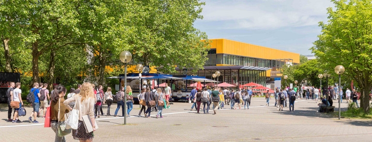 Students on the North Campus with the main cafeteria in the background in summer 