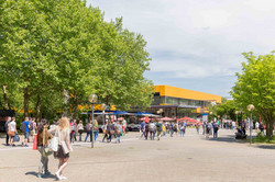 Studierende auf dem Campus Nord mit der Hauptmensa im Hintergrund im Sommer