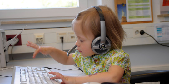 Children_04 Toddler with headphones typing on keyboard.
