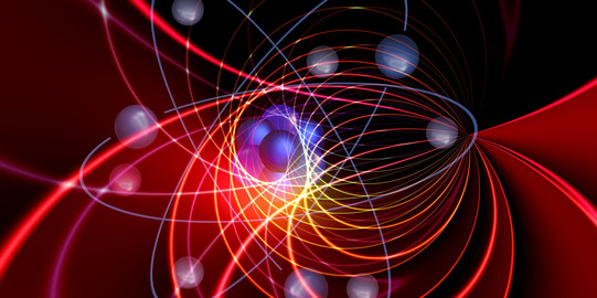 Teilchenphysik Das Bild zeigt mehrere dichtaneinander gedrängte blaue Kugeln, die von farbigen Linien und weiteren Kugeln umgeben werden.