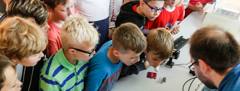 KinderUni im U Kinder im Grundschulalter schauen sich Versuchsanordnung an