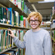 Bücherrecherche in der Bibliothek Studierender steht an einem Bücherregal in der Bibliothek.