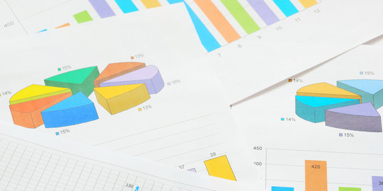 Bunte Kreis- und Balkendiagramme und ein Graph im Detail auf verschiedenen Seiten, die übereinander liegen. 