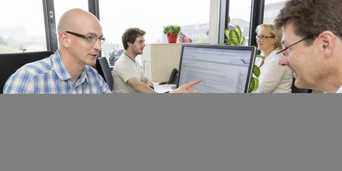 Ein Mann sitzt in einer Beratungssituation vom ITMC Servicedesk gegenüber einem anderen Mann.
