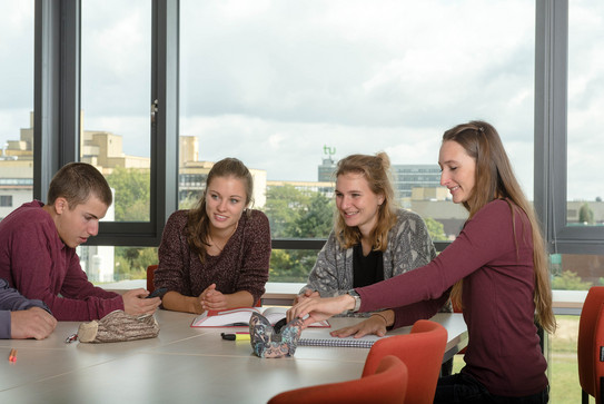A group of students sitting on a desk with study material