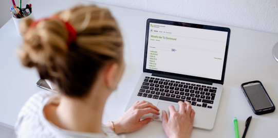 Foto einer Frau, die auf einen Laptop blickt.