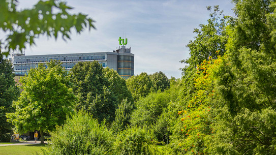 TU Dortmund im Sommer_01 Das Mathematikgebäude mit grünen Bäumen im Vordergrund.