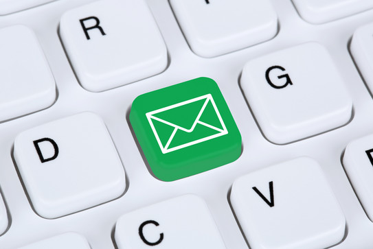 Detail of a white computer keyboard including a green button with a white envelope symbol