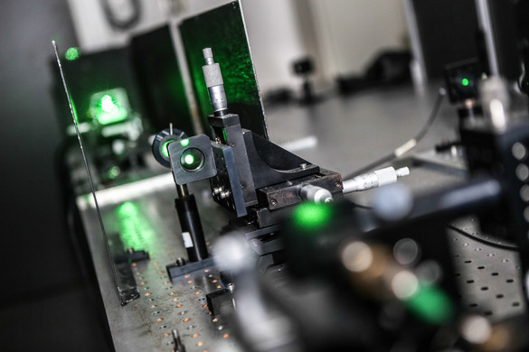Eine Detailaufnahme eines Lasers im Labor in grünen Farben.