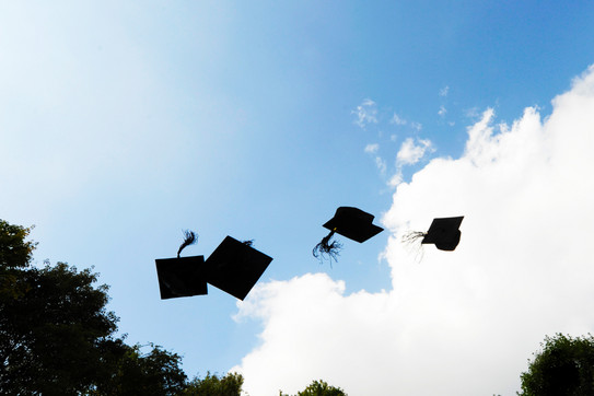 Doctor hats Four black doctor hats flying in the air in front of blue sky with white clouds.