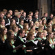 Universitätschor Ein Chor steht in einer Kirche, hält Gesangsbücher in der Hand und singt.