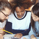 Studierende mit Unterlagen Drei Studierende haben ihre Köpfe über Unterlagen zusammengesteckt.